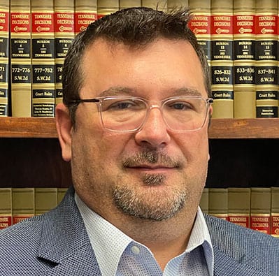 Image of Robert Maines, Esq., in front of a bookshelf filled with legal books. - Maines Legal