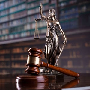 A lawyer statue stands beside a gavel, symbolizing justice and the legal profession - Maines Legal